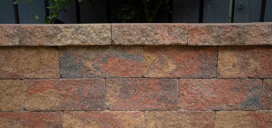 Close-up of Tobermore textured garden walling blocks in blended red and brown tones.